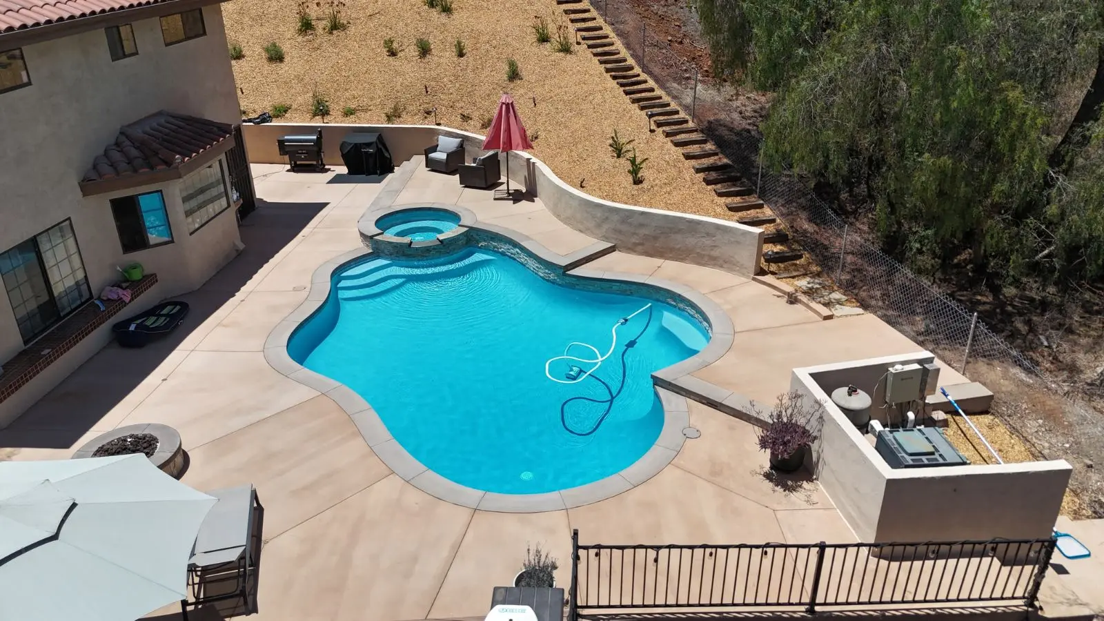 Aerial view of pool and raised stacked-stone spa on hillside property in Escondido