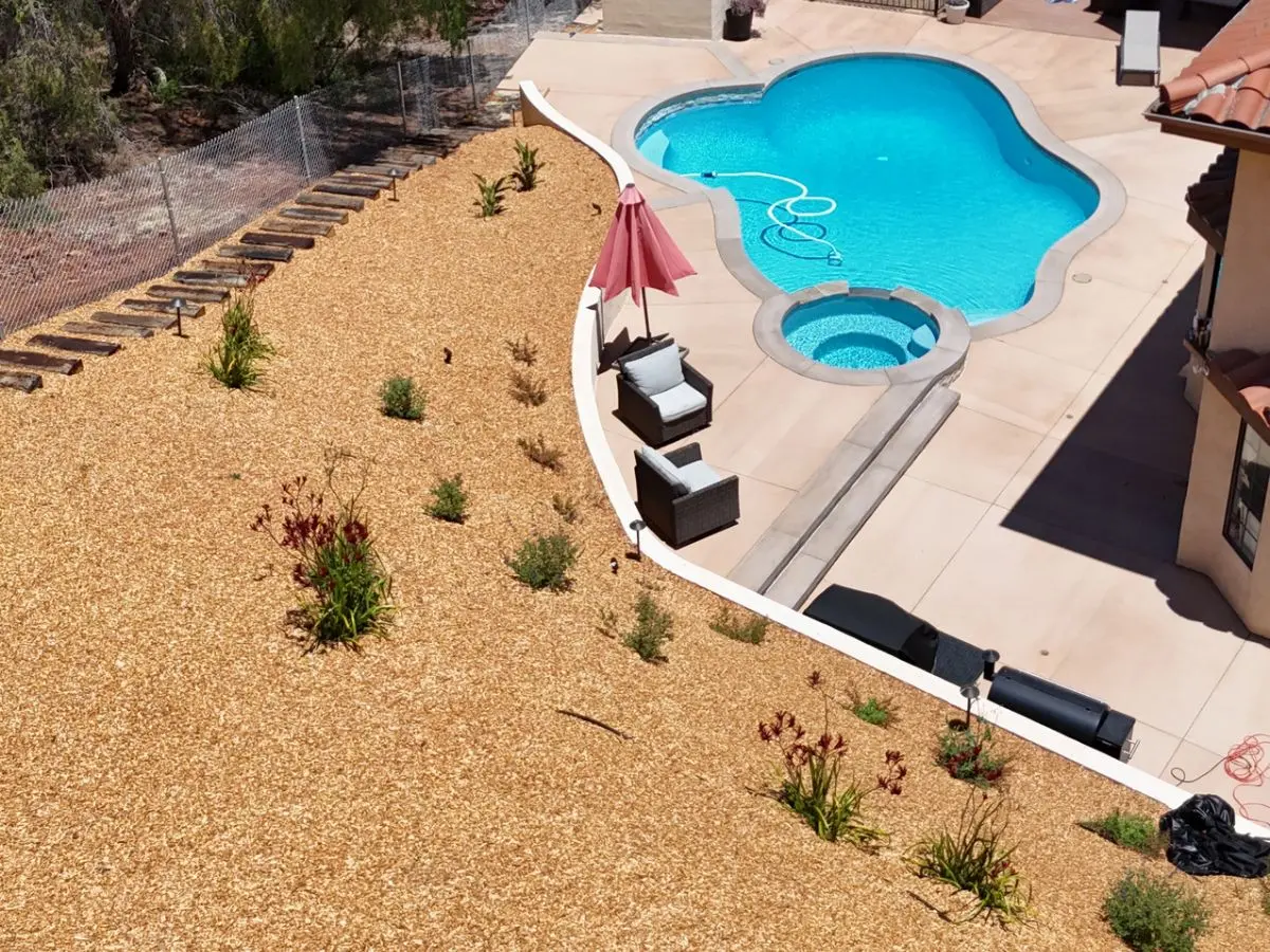 Backyard slope finished with mulch, drought-tolerant plantings and a curved retaining edge