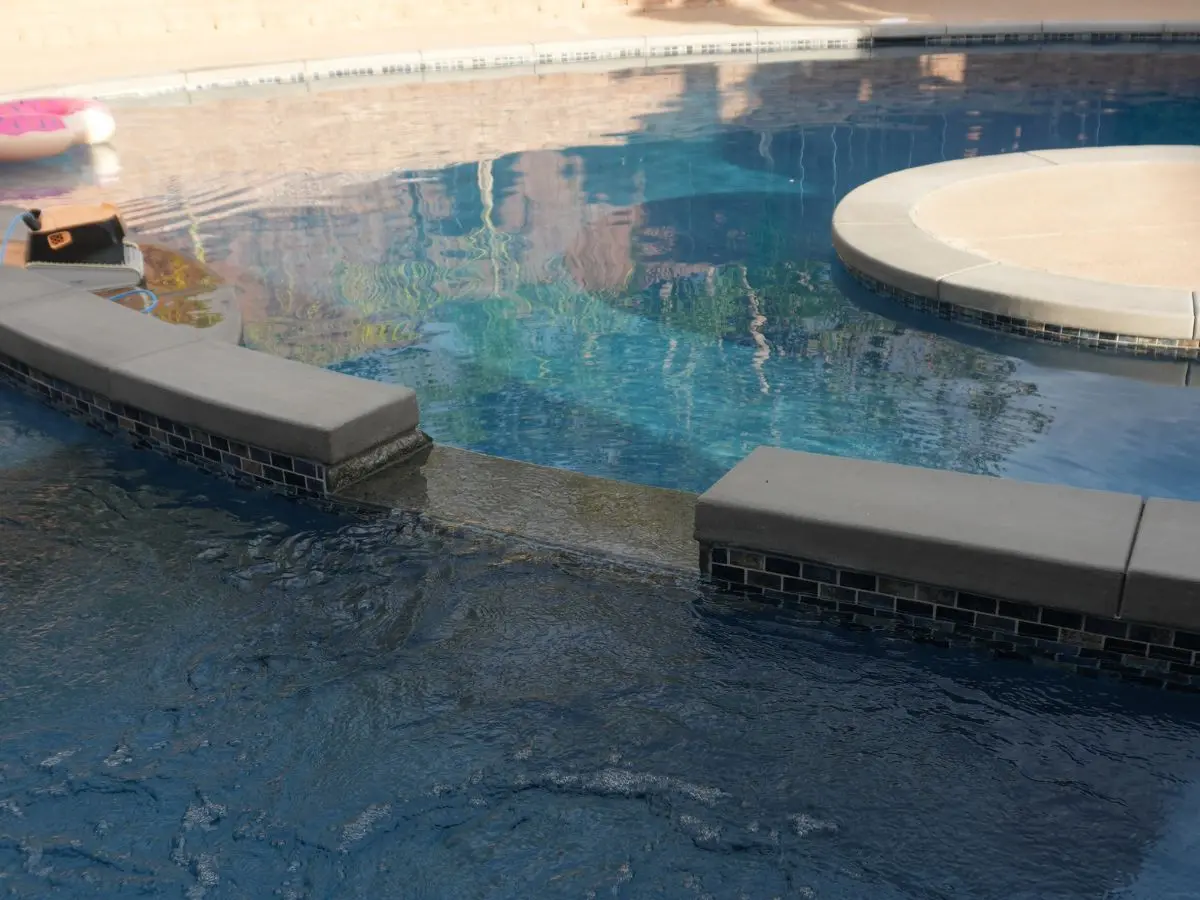 Raised spa spilling over into an adjoining pool with tiled bench seating